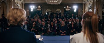 Movie still from “Marry Me” (2022), directed by Kat Coiro – A group of people sitting in front of a microphone; Wide shot, High angle