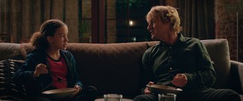 Movie still from “Marry Me” (2022), directed by Kat Coiro – Two people are sitting on a couch talking to each other; Medium shot, Over the shoulder angle