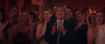 Movie still from “Marry Me” (2022), directed by Kat Coiro – A group of people in a room clapping and smiling; Close Up shot, Over the shoulder angle
