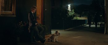 Movie still from “Marry Me” (2022), directed by Kat Coiro – A man sitting next to a dog on a leash; Wide shot, Low angle