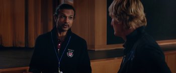 Movie still from “Marry Me” (2022), directed by Kat Coiro – A man in a black jacket talking to another man in a black jacket; Medium shot, Over the shoulder angle