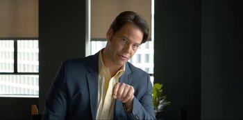 Movie still from “Maximum Truth” (2023), directed by David Stassen – A person wearing a suit and tie; Medium shot, Over the shoulder angle