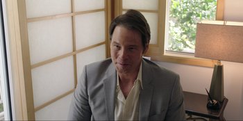 Movie still from “Maximum Truth” (2023), directed by David Stassen – A person wearing a suit and tie; Close Up shot, Over the shoulder angle