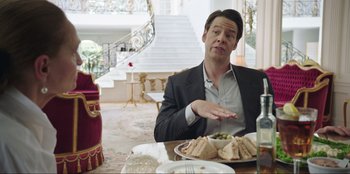 Movie still from “Maximum Truth” (2023), directed by David Stassen – A man sitting at a table with a plate of food; Medium shot, Over the shoulder angle