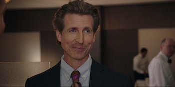 Movie still from “Maximum Truth” (2023), directed by David Stassen – A person wearing a suit and tie; Close Up shot, Over the shoulder angle