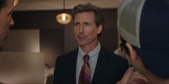 Movie still from “Maximum Truth” (2023), directed by David Stassen – A person wearing a suit and a tie; Close Up shot, Over the shoulder angle