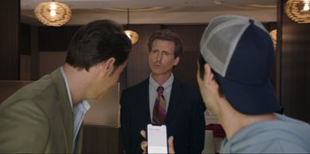Movie still from “Maximum Truth” (2023), directed by David Stassen – A man looking at himself in the mirror while holding a cell phone; Medium shot, Over the shoulder angle