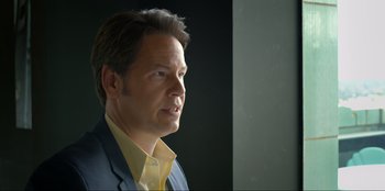 Movie still from “Maximum Truth” (2023), directed by David Stassen – A person wearing a suit and tie; Close Up shot, Low angle