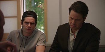 Movie still from “Maximum Truth” (2023), directed by David Stassen – Two men sitting next to each other in front of a window; Close Up shot, Over the shoulder angle