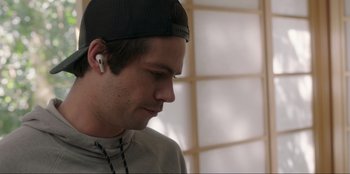 Movie still from “Maximum Truth” (2023), directed by David Stassen – A young man wearing a baseball cap and ear buds; Close Up shot, Over the shoulder angle
