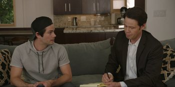 Movie still from “Maximum Truth” (2023), directed by David Stassen – Two men sitting on a couch in a living room; Medium shot, Over the shoulder angle