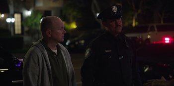 Movie still from “Maximum Truth” (2023), directed by David Stassen – Two police officers standing next to each other on a street; Medium shot, Over the shoulder angle
