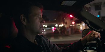 Movie still from “Maximum Truth” (2023), directed by David Stassen – A man sitting in the driver's seat of a car at night; Close Up shot, Low angle