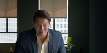 Movie still from “Maximum Truth” (2023), directed by David Stassen – A person wearing a suit and tie; Medium shot, Low angle