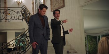 Movie still from “Maximum Truth” (2023), directed by David Stassen – Two men standing next to each other in a room; Medium shot, Over the shoulder angle