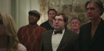 Movie still from “Maximum Truth” (2023), directed by David Stassen – A group of men standing next to each other in front of a chandelier; Medium shot, Low angle