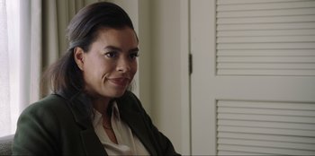 Movie still from “Maximum Truth” (2023), directed by David Stassen – A person sitting in front of a window; Close Up shot, Over the shoulder angle