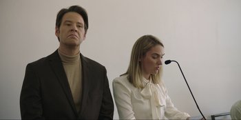 Movie still from “Maximum Truth” (2023), directed by David Stassen – A man and a woman standing next to each other in front of microphones; Medium shot, Low angle