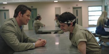 Movie still from “Maximum Truth” (2023), directed by David Stassen – Two men sitting at a table talking to each other; Medium shot, Over the shoulder angle