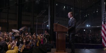 A man is speaking at a podium in front of a crowd of onlookers
