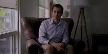 A man sitting on a brown leather chair in a living room