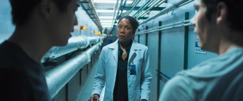 Movie still from “Maze Runner: The Scorch Trials” (2015), directed by Wes Ball – A woman wearing a lab coat walking down a hallway; Medium shot, Over the shoulder angle