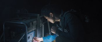 Movie still from “Maze Runner: The Scorch Trials” (2015), directed by Wes Ball – A young man looking at an electronic device in the dark; Close Up shot, Low angle