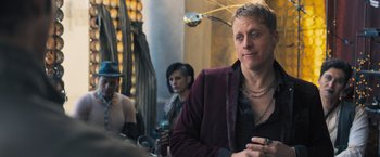 Movie still from “Maze Runner: The Scorch Trials” (2015), directed by Wes Ball – A man in a purple jacket sitting in front of a mirror; Medium shot, Over the shoulder angle
