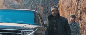 Movie still from “Maze Runner: The Scorch Trials” (2015), directed by Wes Ball – A man standing in front of an old truck; Medium shot, Over the shoulder angle