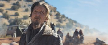 Movie still from “Maze Runner: The Scorch Trials” (2015), directed by Wes Ball – A man with long hair and a goatee is standing in front of a group of people; Medium shot, Over the shoulder angle