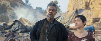 Movie still from “Maze Runner: The Scorch Trials” (2015), directed by Wes Ball – A man standing in front of a building with smoke coming out of it; Medium shot, Low angle
