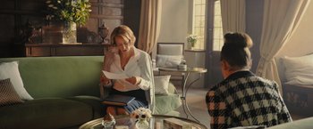 Movie still from “Me Before You” (2016), directed by Thea Sharrock – A woman sitting at a table reading a piece of paper; Medium shot, Over the shoulder angle