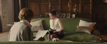 Movie still from “Me Before You” (2016), directed by Thea Sharrock – A woman sitting on top of a green couch next to another woman; Medium shot, Over the shoulder angle