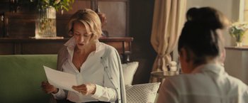 Movie still from “Me Before You” (2016), directed by Thea Sharrock – A woman sitting on a chair looking at a phone; Medium shot, Over the shoulder angle