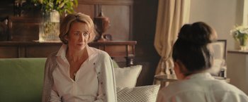 Movie still from “Me Before You” (2016), directed by Thea Sharrock – A woman sitting on a chair in a living room; Medium shot, Over the shoulder angle