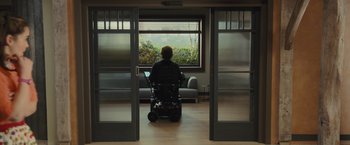 Movie still from “Me Before You” (2016), directed by Thea Sharrock – A person in a wheelchair looking out a window; Wide shot, Over the shoulder angle
