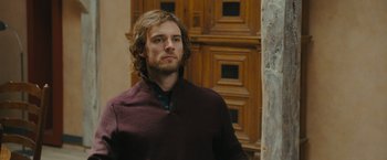 Movie still from “Me Before You” (2016), directed by Thea Sharrock – A man with long brown hair wearing a maroon sweater; Close Up shot, Over the shoulder angle