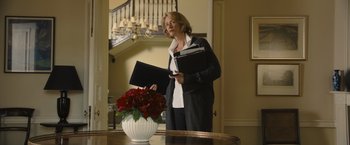 Movie still from “Me Before You” (2016), directed by Thea Sharrock – A woman standing in front of a table with a vase of flowers; Medium shot, Low angle