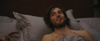Movie still from “Me Before You” (2016), directed by Thea Sharrock – A man laying in a bed with a blanket on top of him; Close Up shot, Over the shoulder angle