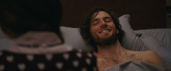 Movie still from “Me Before You” (2016), directed by Thea Sharrock – A man with long hair laying in a hospital bed; Close Up shot, Over the shoulder angle