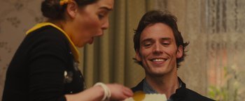 Movie still from “Me Before You” (2016), directed by Thea Sharrock – A man smiles as a woman holds a piece of cake; Close Up shot, Over the shoulder angle