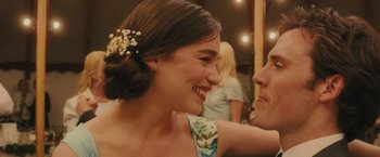 Movie still from “Me Before You” (2016), directed by Thea Sharrock – A woman with a flower in her hair smiling at a man; Close Up shot, Over the shoulder angle