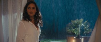 Movie still from “Me Before You” (2016), directed by Thea Sharrock – A woman standing in front of a tree in the rain; Medium shot, Over the shoulder angle