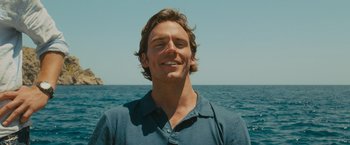 Movie still from “Me Before You” (2016), directed by Thea Sharrock – A man standing in front of the ocean smiling for the camera; Close Up shot, Low angle
