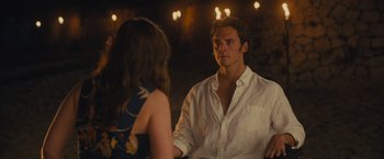 Movie still from “Me Before You” (2016), directed by Thea Sharrock – A man and a woman are sitting in front of each other in front of lights; Medium shot, Over the shoulder angle