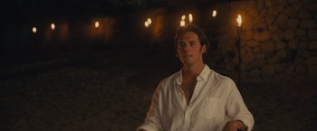 Movie still from “Me Before You” (2016), directed by Thea Sharrock – A man in a white shirt is standing in front of lights; Medium shot, Over the shoulder angle