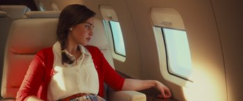 Movie still from “Me Before You” (2016), directed by Thea Sharrock – A woman sitting on a seat on a plane looking out the window; Medium shot, Over the shoulder angle