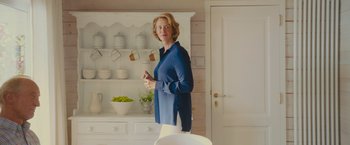 Movie still from “Me Before You” (2016), directed by Thea Sharrock – A woman standing in front of a white cabinet; Medium shot, Low angle