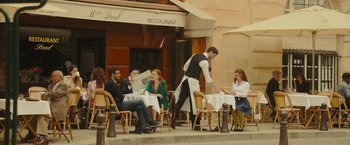 Movie still from “Me Before You” (2016), directed by Thea Sharrock – A group of diners sitting at tables outside of a restaurant; Wide shot, High angle