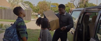 Movie still from “Me Time” (2022), directed by John Hamburg – A man handing a cardboard box to a young girl; Medium shot, Over the shoulder angle
